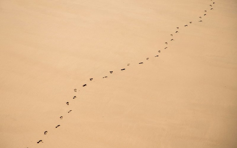 Photographie aérienne d'une piste d'empreintes de pas continue dans le sable.