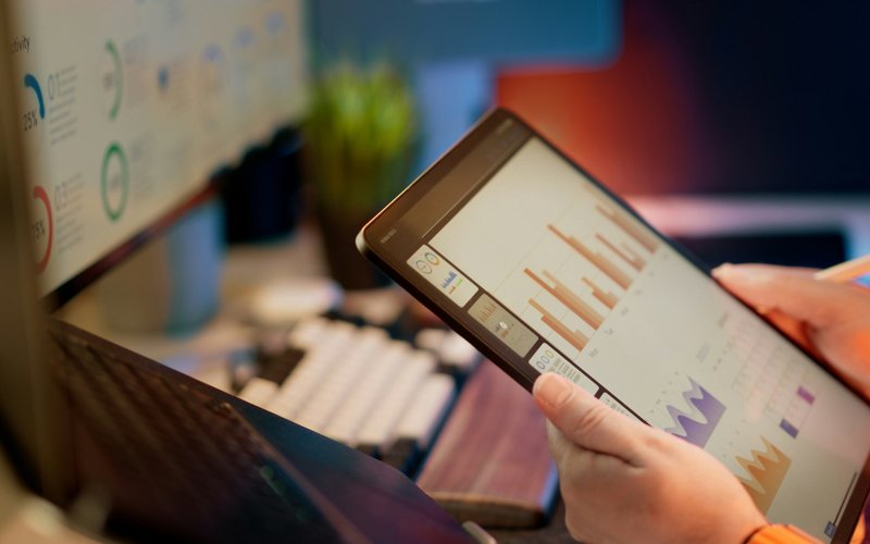 Une personne analyse des données financières affichées sur une tablette.